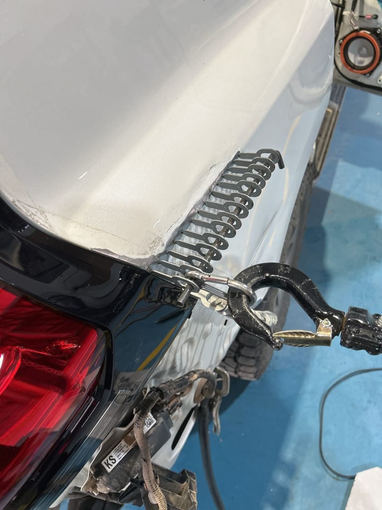 Close-up of stud-weld pull tabs drawing the Prado's rear quarter panel back into shape