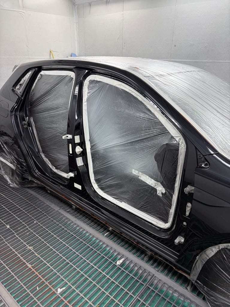 Meticulous masking on a black car being prepared for paint