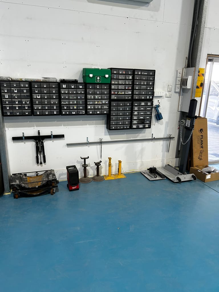 Wall of labelled parts drawers, first aid kit and panel-repair tools in the Aldinga Crash Repairs workshop
